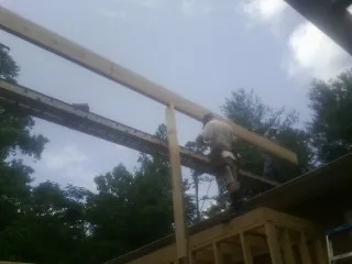 Carpenter setting a ridge beam over a new addition frame — Ice Dam Removal by Roofing Brothers in Guys