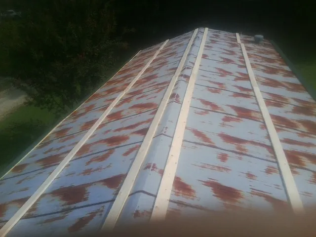Rusted metal roof panels with new wood purlins before replacement — Storm Damage Roof Repair in Guys by Roofing Brothers