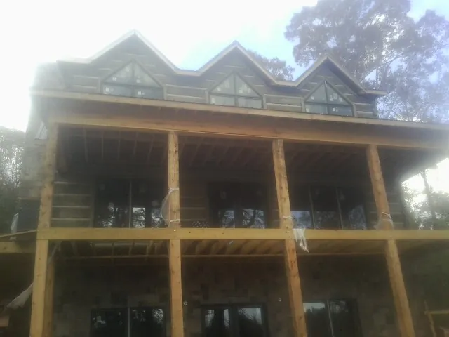 Dormers and porch framing on a large log home under construction — Roof Coating work by our crew in Guys