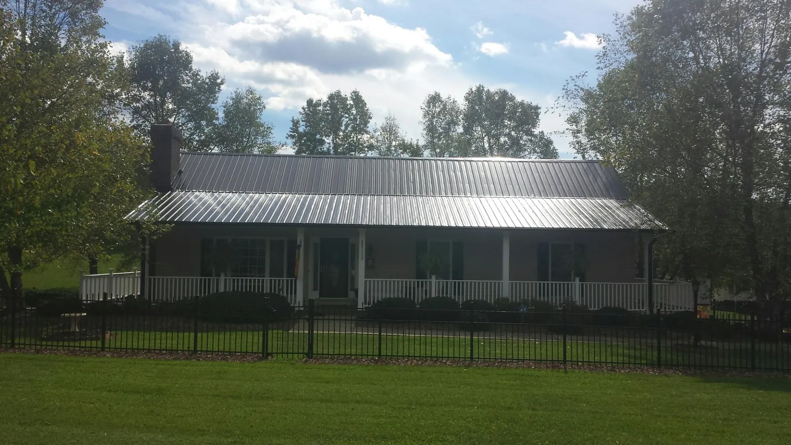 Gray metal roof on a brick ranch with a full width front porch — Gutter Guard Installation work by our crew in Guys