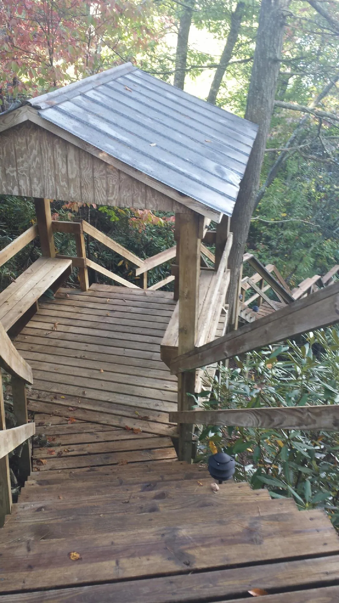 Metal roofed shelter over wooden steps on a wooded walkway — Skylight Repair & Installation work by our crew in Guys