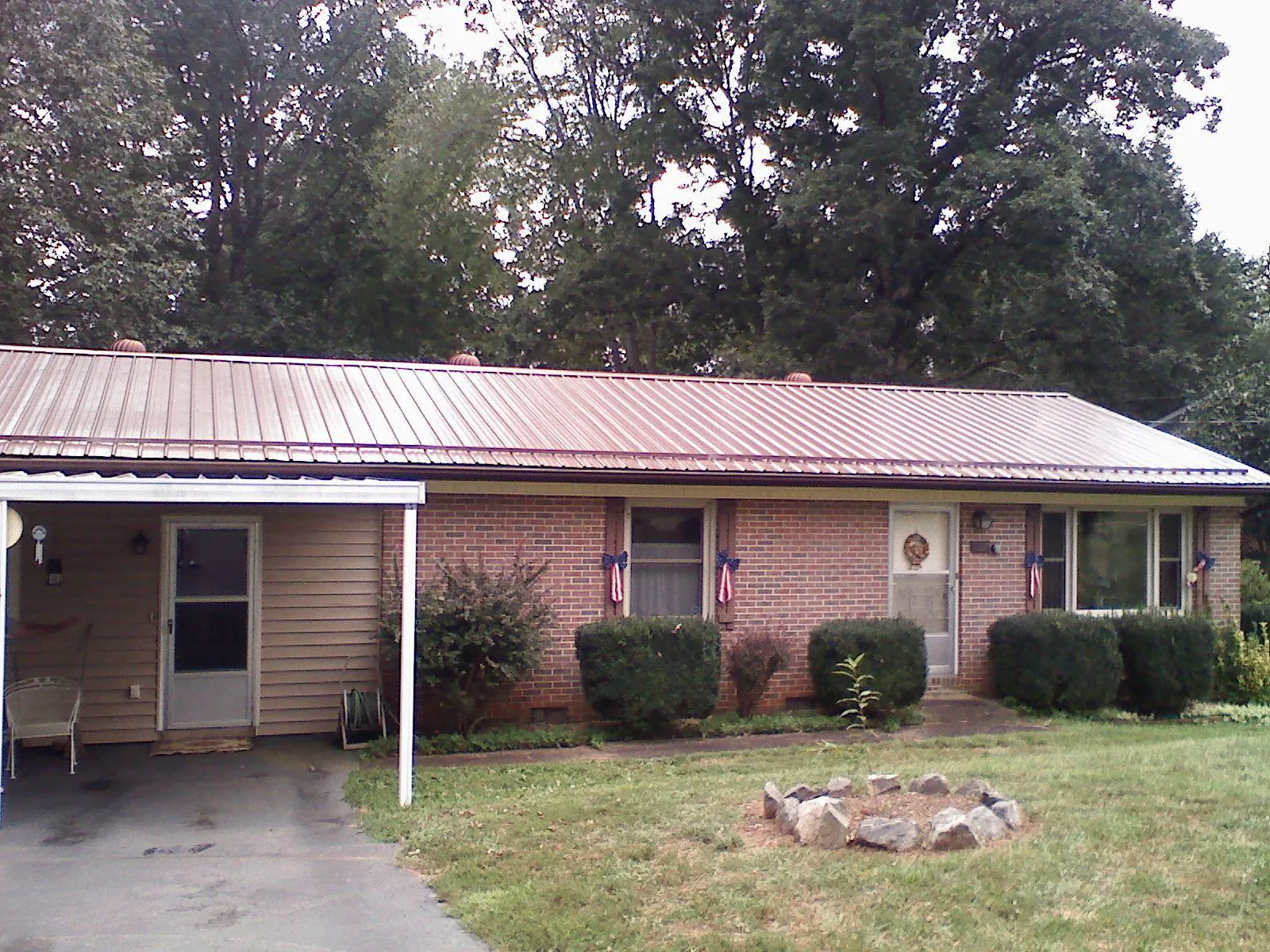 Bronze metal roof and carport on a brick ranch home — Roof Repair work by our crew in Guys